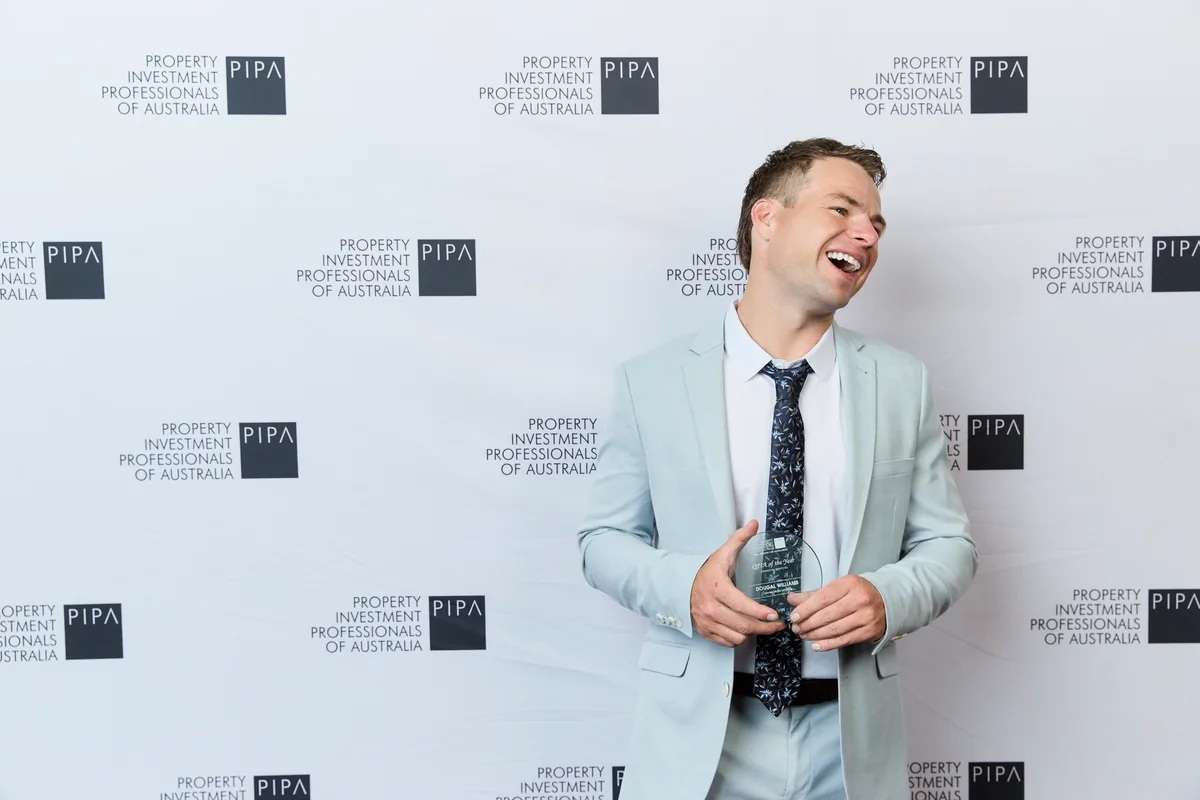 Dougal Williams of Money Sense Lending holding the PIPA QPIA of the Year – Financial Services 2026 award in front of the Property Investment Professionals of Australia media wall